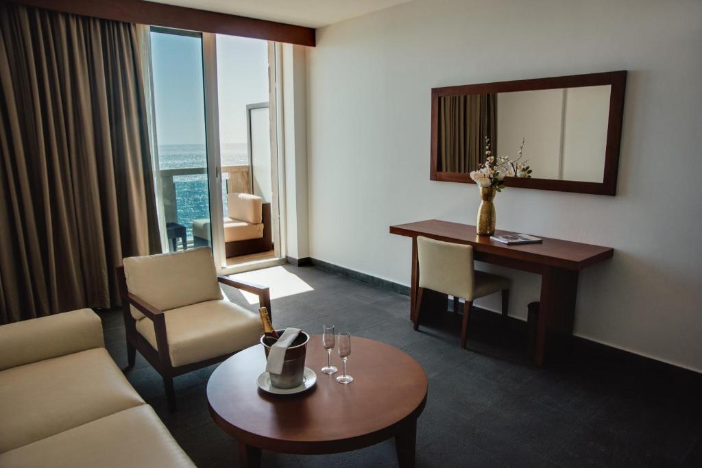 Mūsdienīgs viesnīcas numurs ar jūras skatu, kurā ir ērtas mēbeles, rakstāmgalds un dekora elementi. Gaismas plūsma caur lielajiem logiem rada patīkamu atmosfēru.