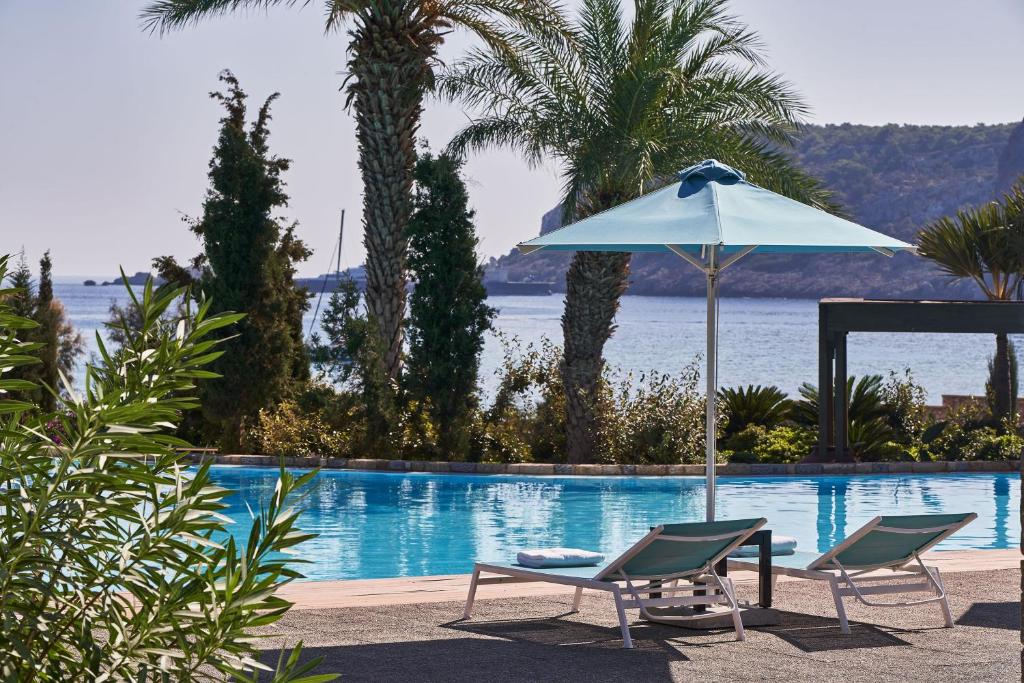 AquaGrand Exclusive Deluxe Resort baseins ar palmām un skatu uz piekrasti.