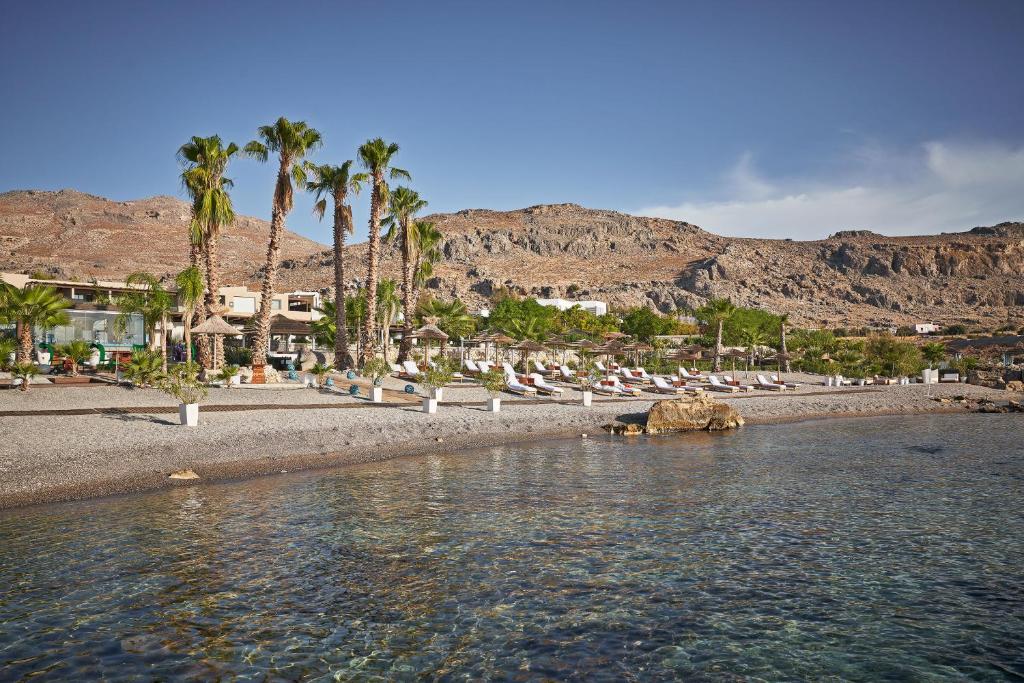 Aquagrand Exclusive Deluxe Resort piekrastē ar palmām un sauļošanās krēsliem