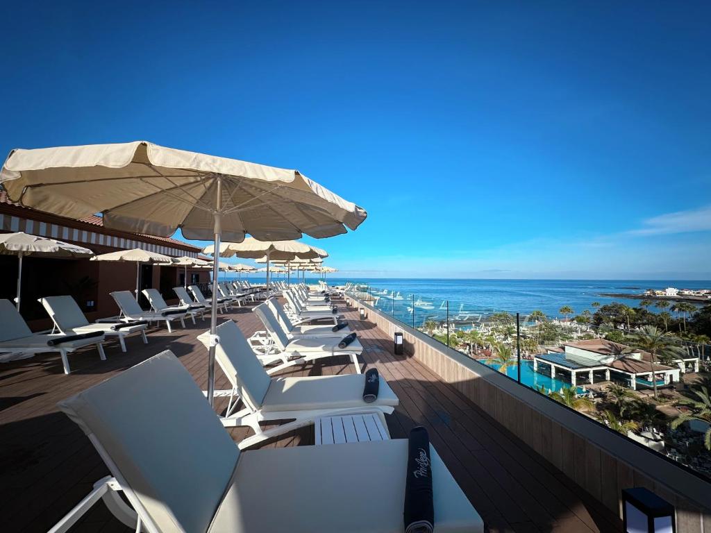 Sauļošanās vieta ar pludmales krēsliem un lietussargiem, kas piedāvā skatu uz jūru un apkārtējo ainavu. Ideāla vieta atpūtai saulainā dienā.