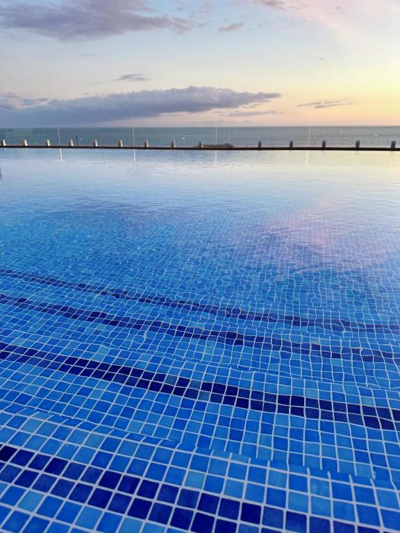 Peldbaseins ar zilajiem flīzēm, kas atspoguļo saulrietu un jūras skatu. Klusa un relaksējoša atmosfēra.