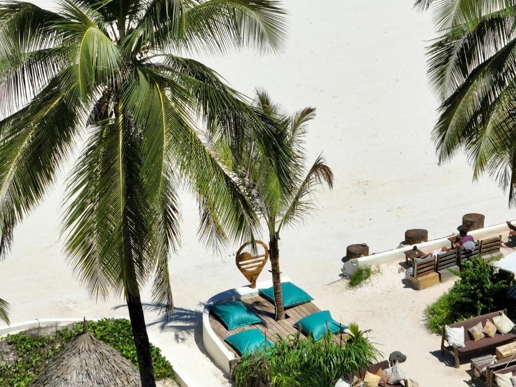 Mahali Zanzibar pludmales atpūtas zona ar palmām un sauļošanās krēsliem.