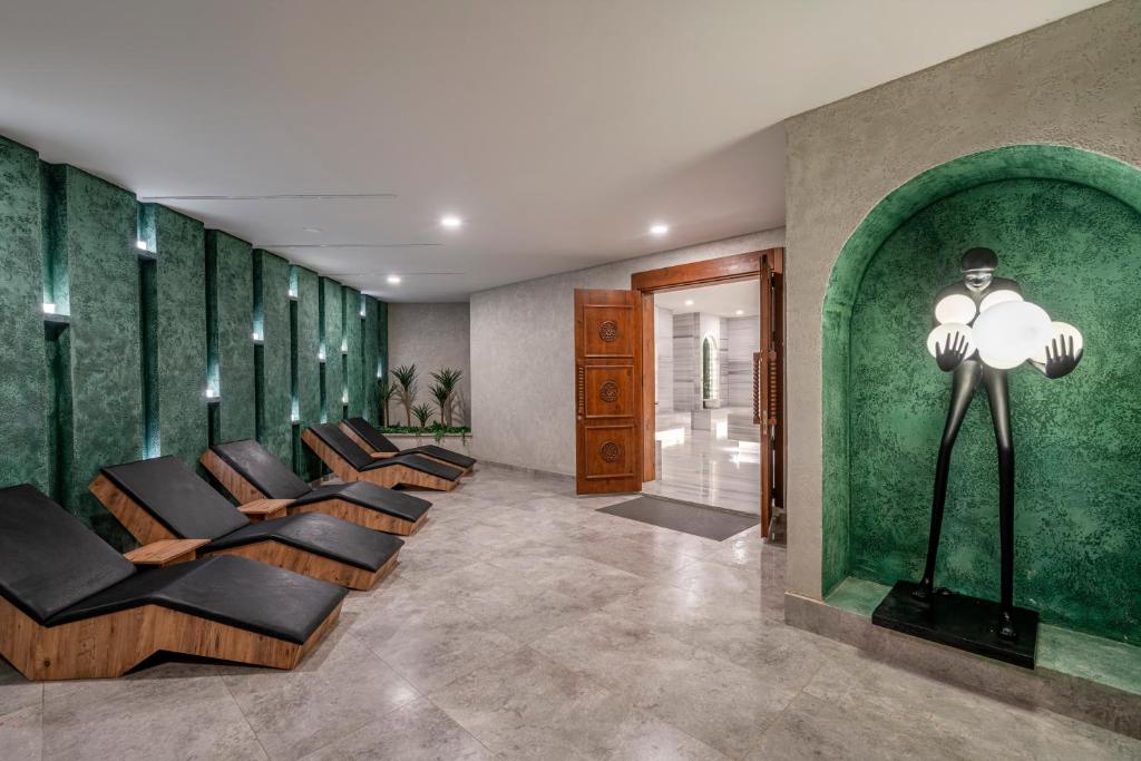 Mūsdienīgs spa interjers ar ērtām atpūtas krēslām un unikālu mākslas objektu, kas pievieno stilīgu akcentu. Zaļās sienas un eleganta apgaismojuma kombinācija rada relaksējošu atmosfēru.
