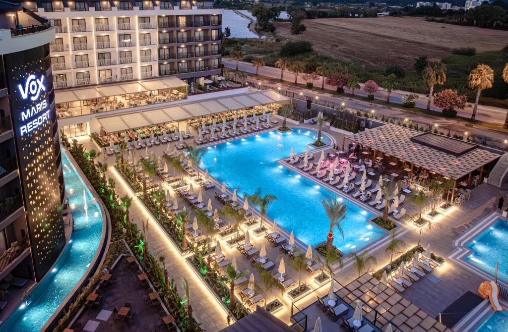 Luksusa viesnīca ar plašu baseinu un atpūtas zonām, kas apgaismotas vakara gaismās. Vides elementi un palmās papildina kūrorta atmosfēru.