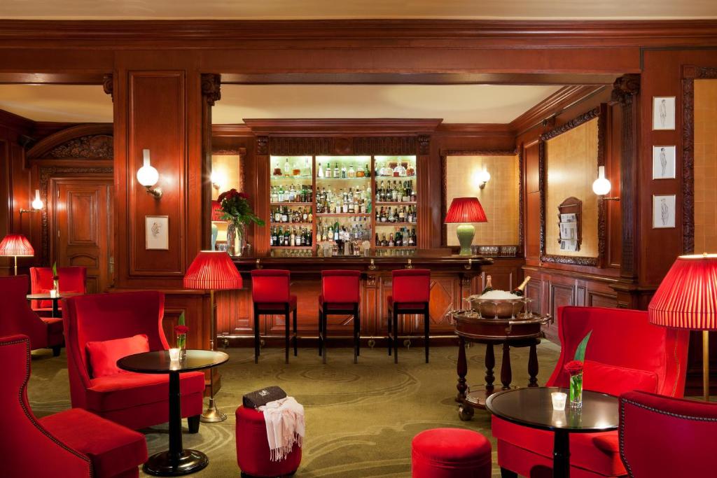 Eleganta bāra zona viesnīcā Hôtel Barrière Le Royal Deauville ar sarkaniem krēsliem.