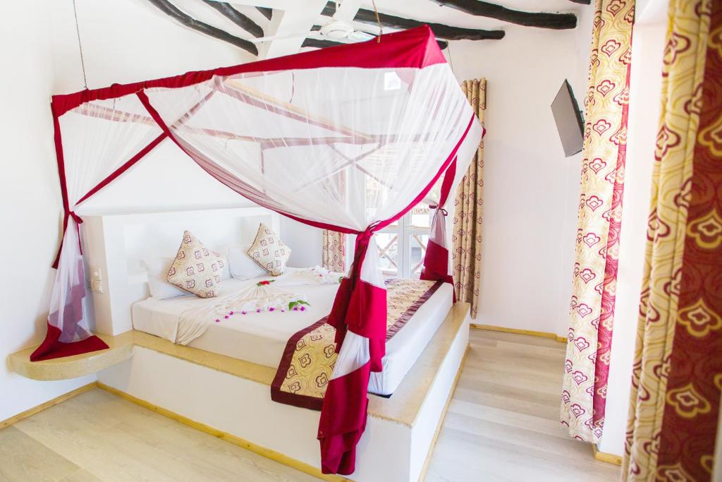 AHG Dream's Bay Beach numurs ar baldahīnu un ziediem uz gultas.