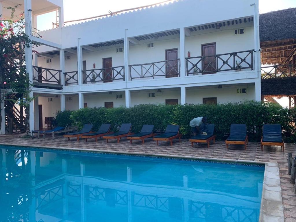 Isla Bonita Zanzibar Beach Resort baseins ar sauļošanās krēsliem.