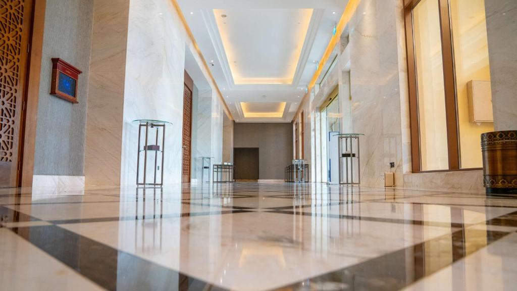 Marmora grīda un modernas interjera detaļas greznā koridorā ar izsmalcinātiem apgaismojuma risinājumiem. Ideāli piemērots luksusa viesnīcu vai komerciālu telpu attēlošanai.