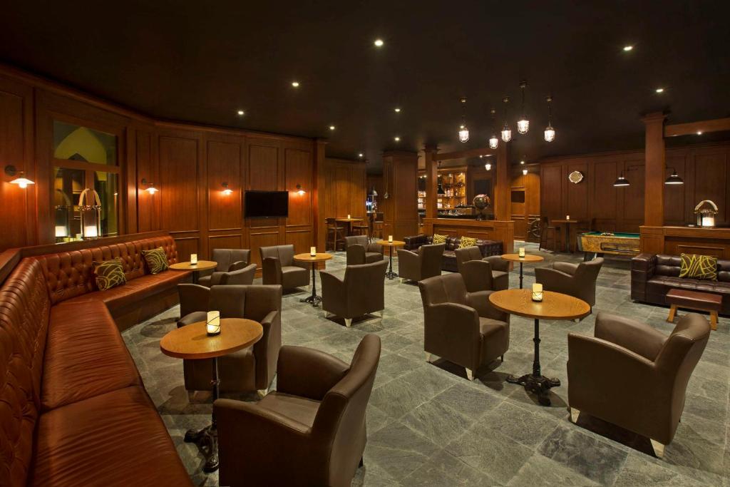 Elegants bārs ar tumšām koka sienām, mīkstām ādas mēbelēm un zemu apgaismojumu, radot intīmu atmosfēru. Interjerā ir stilīgi galdi un krēsli, kas aicina uz relaksāciju.