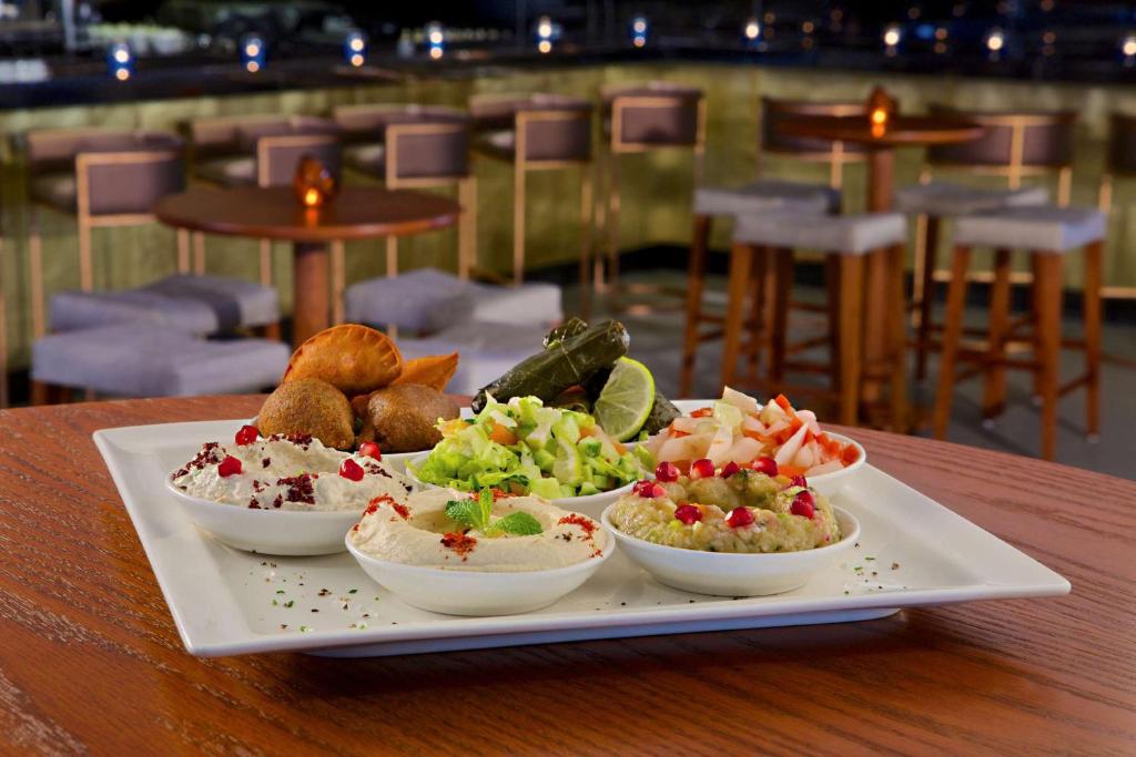 Bagātīgs uzkodu šķīvis ar dažādām mērcēm, dārzeņiem un ceptām uzkodām, pasniegts eleganti noformētā restorānā. Ideāls piedāvājums gardēžiem.