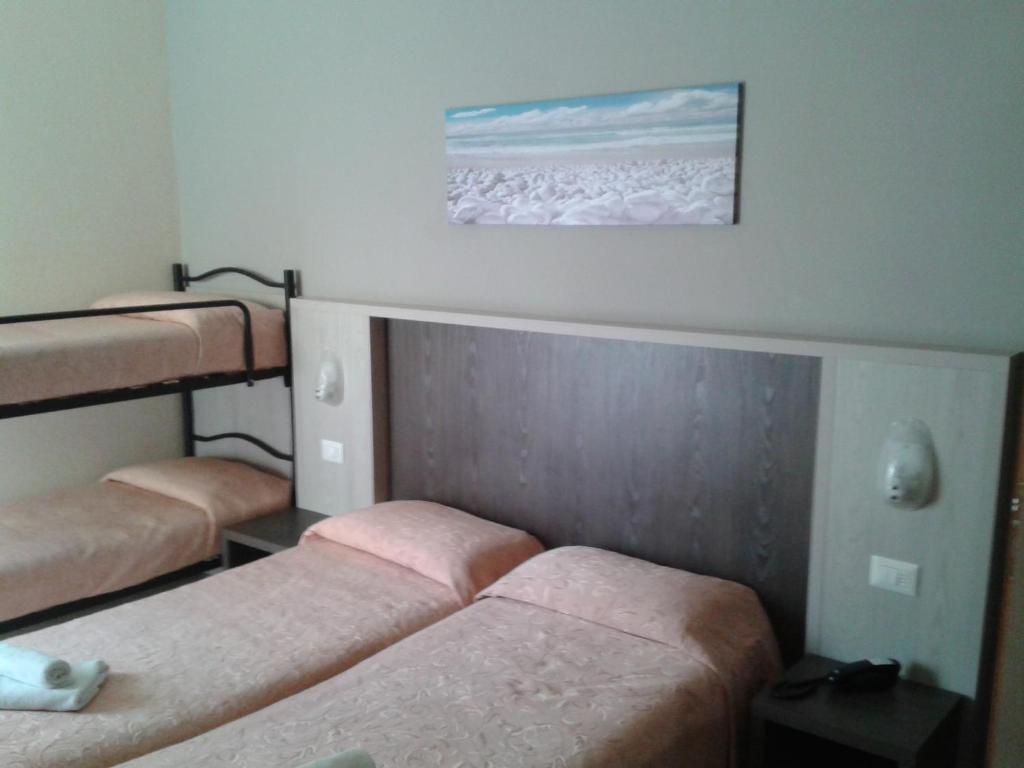 Vienkāršs viesnīcas numurs ar divām atsevišķām gultām un divguļamo gultu, kas atrodas fonā. Uz sienas ir ainava ar pludmales skatu. Numurā ir pamata mēbeles un gaismas avoti.