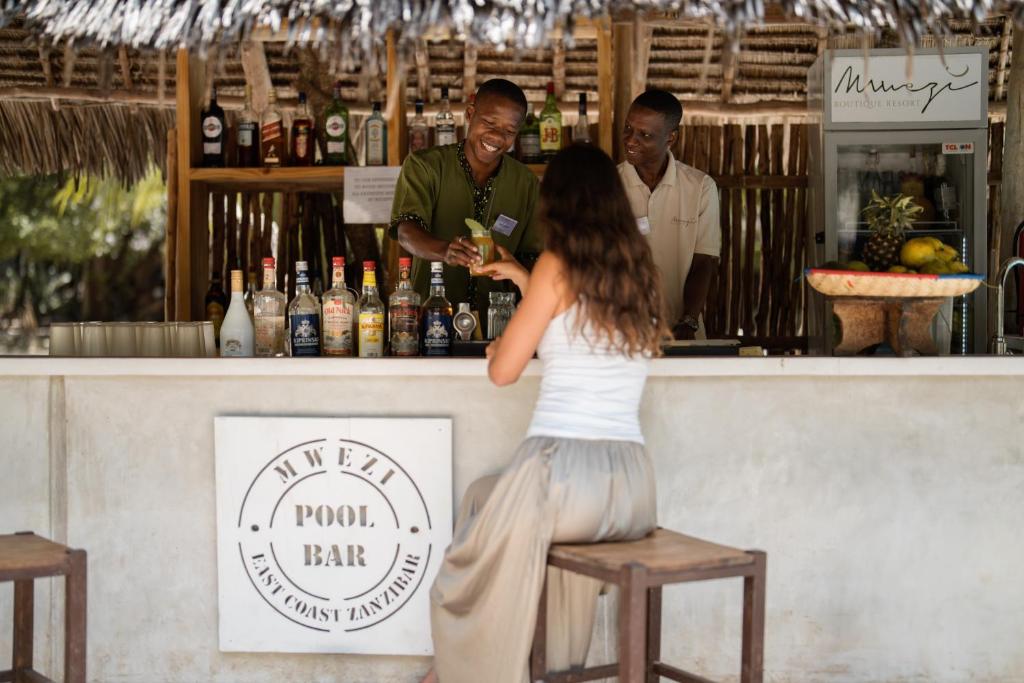 Mwezi Boutique Resort bārs ar viesiem pie baseina.