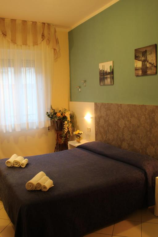 Mūsdienīgs viesnīcas numurs ar tumši zilu gultasveļu, dekoratīviem attēliem uz sienas un daudz gaismas no loga. Numurā ir arī ziedu kompozīcija un tīra vides atmosfēra.