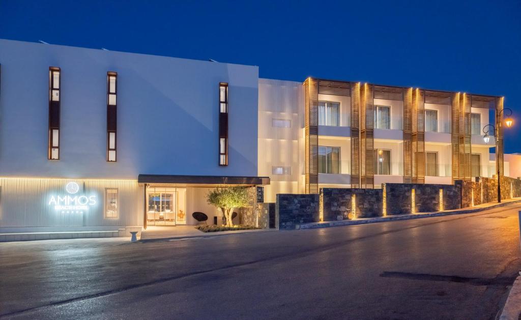 Enorme Ammos Beach Resort naktsmītnes fasāde piekrastē, apgaismotā vakarā.