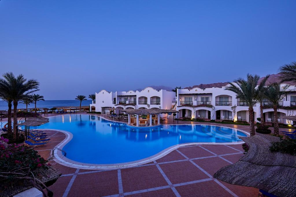 Viesnīca Jaz Dahabeya pie baseina piekrastē, vakara apgaismojumā.