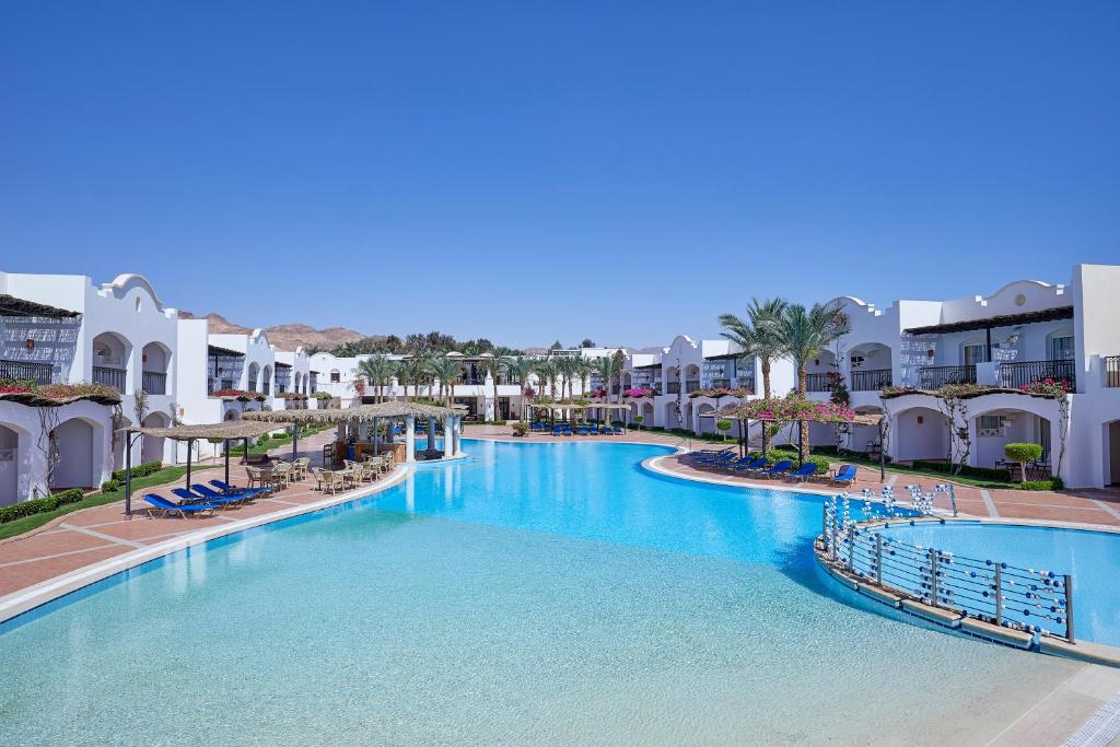 Jaz Dahabeya viesnīca ar plašu baseinu un balto arhitektūru