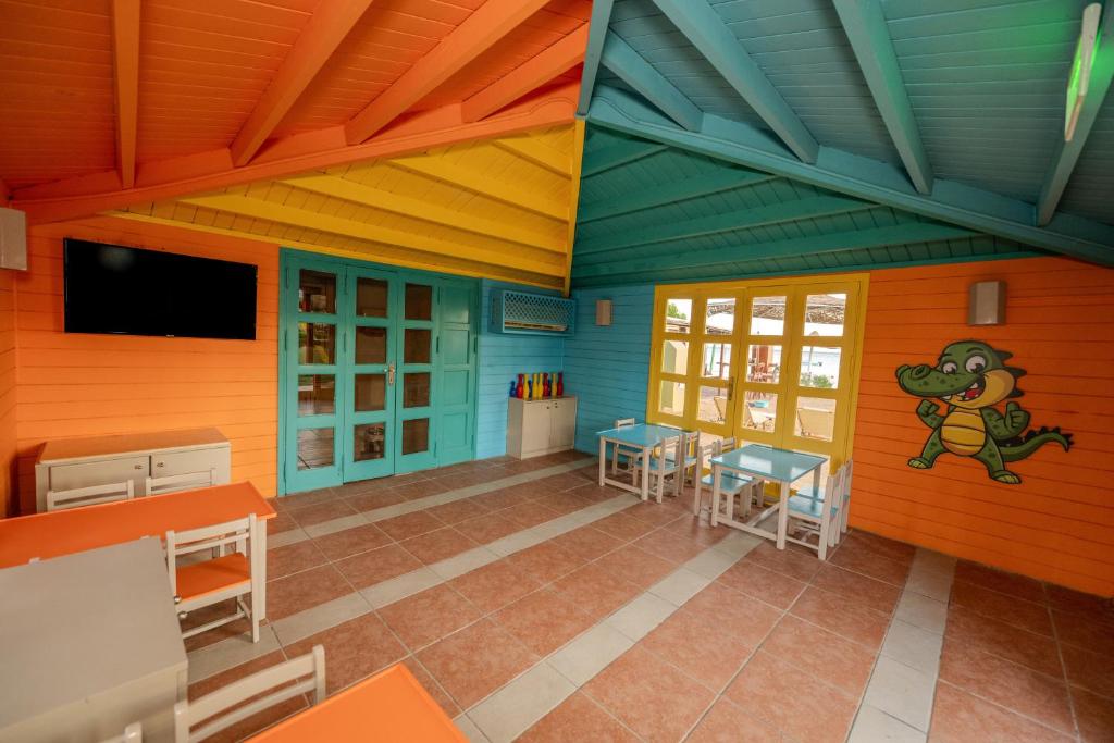 Krāsains bērnu rotaļu stūrītis viesnīcā Jaz Dahabeya ar galdiem un televizoru.