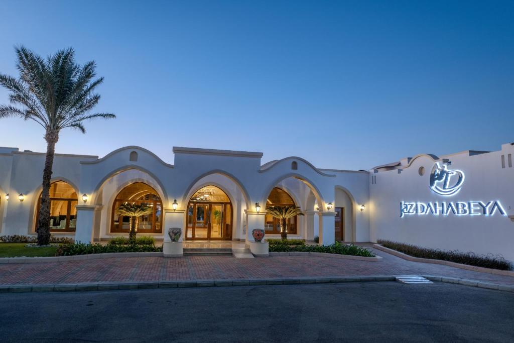 Viesnīcas Jaz Dahabeya ieeja ar palmām un vakara apgaismojumu.