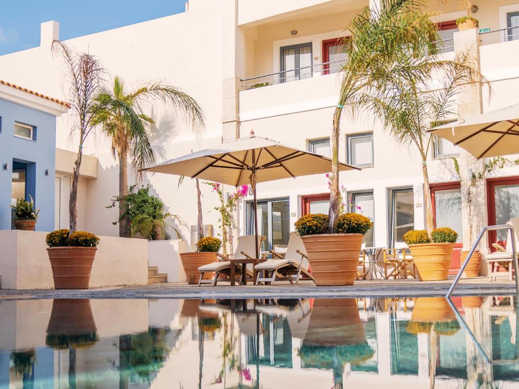 Grecotel Plaza Beach House baseins ar sauļošanās krēsliem un palmu kokiem