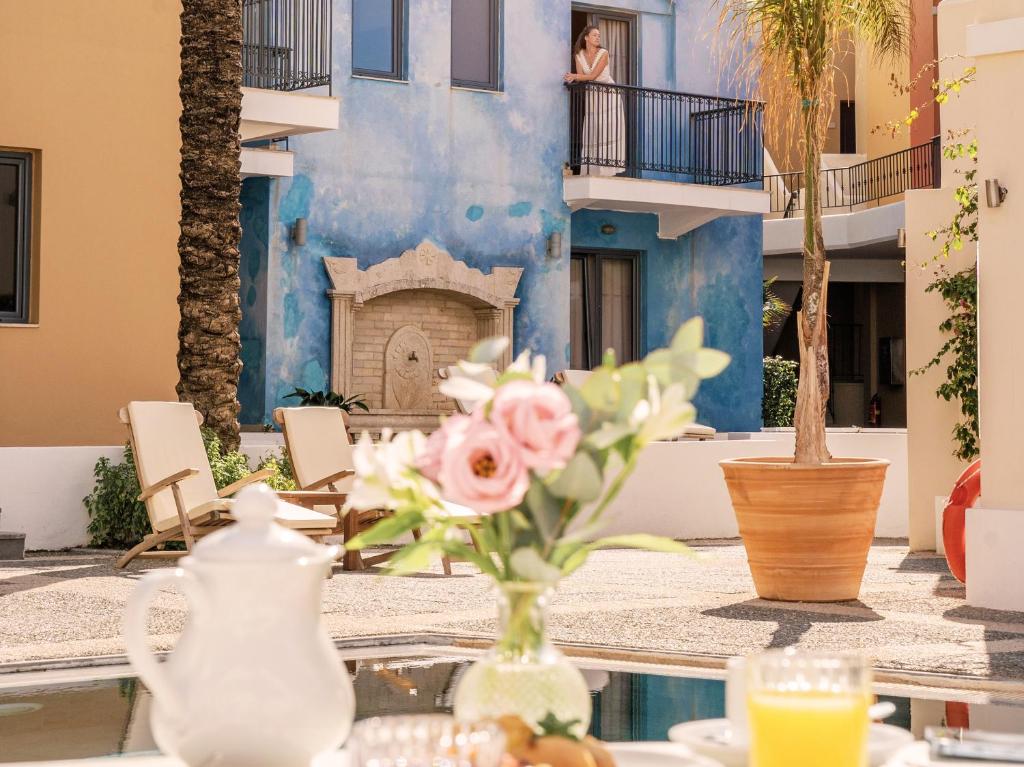 Romantisks brīdis Grecotel Plaza Beach House ar sievieti uz balkona.