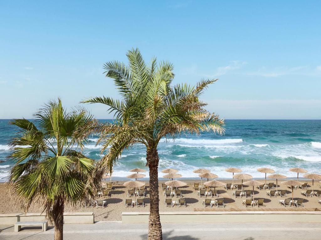 Grecotel Plaza Beach House pludmales skats ar palmu kokiem un saulessargiem