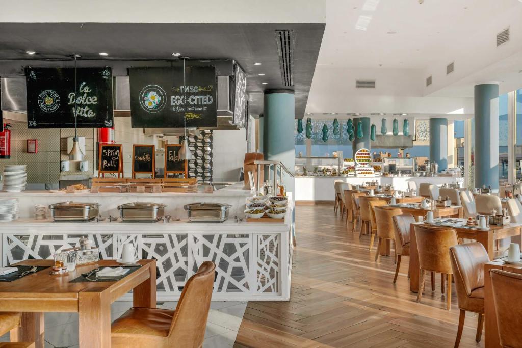 Elegants restorāns ar modernu interjeru, kas ietver plašu ēdienu izvēli un komfortablas sēdvietas. Gaismas un krāsu kombinācija rada patīkamu atmosfēru.