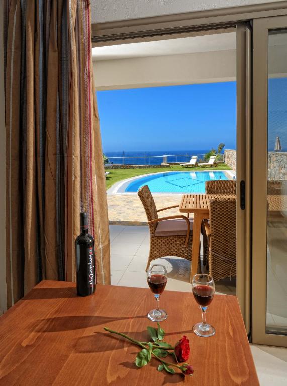 Romantiska ainava ar skatu uz baseinu un jūru, uz galda atrodas sarkanvīns un rozes zieds. Ideāla vieta atpūtai un romantiskām vakariņām.