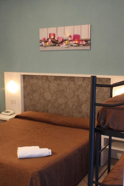 Mūsdienīgs numurs ar brūnu gultas veļu un dekoratīvām svecēm uz sienas. Telpa iekārtota ar vienkāršu, bet elegantu dizainu.