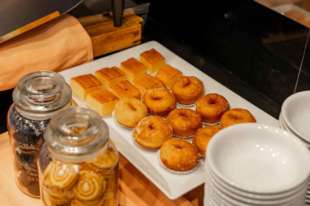Deserts uz galda, tostarp donuti un kūkas, ar sīkdatņu burkām blakus.