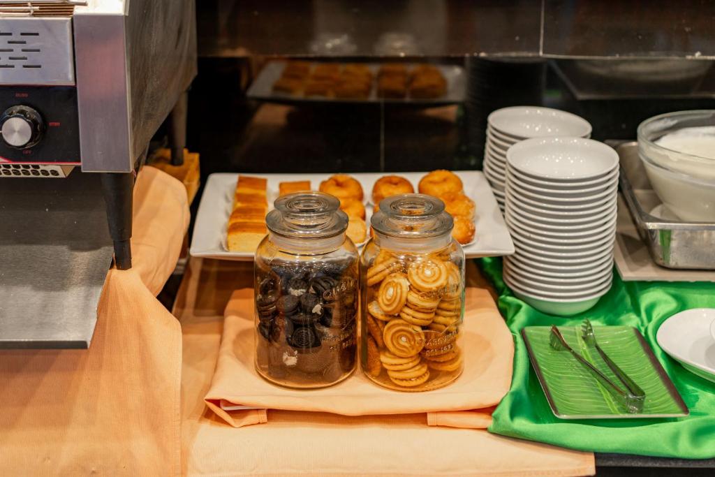 Biskvītu un cepumu burkas uz bufetes galda, blakus ir dažādi trauki un deserti.