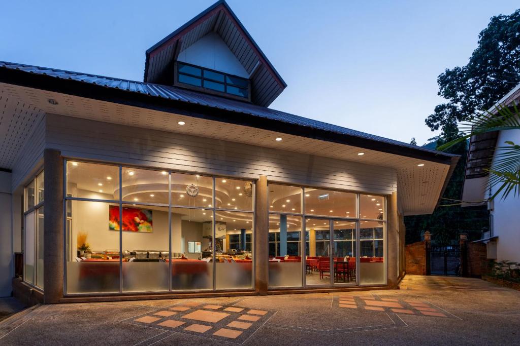 Mūsdienīga restorāna ēka ar plašiem logiem un izgaismotu interjeru, kas redzams vakarā. Ap ēku ir ainaviskas detaļas un ērti sēdvietas.