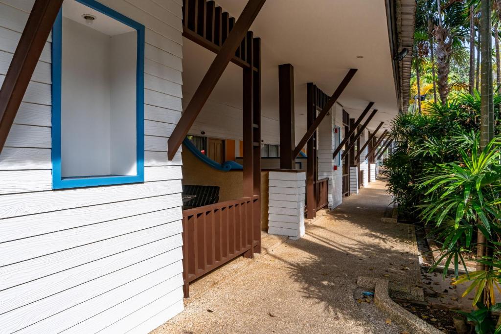 Modernas viesnīcas koridors ar baltiem un brūniem elementiem, apzaļumots ar palmu stādiem. Vietas, kur var atpūsties un baudīt dabu.