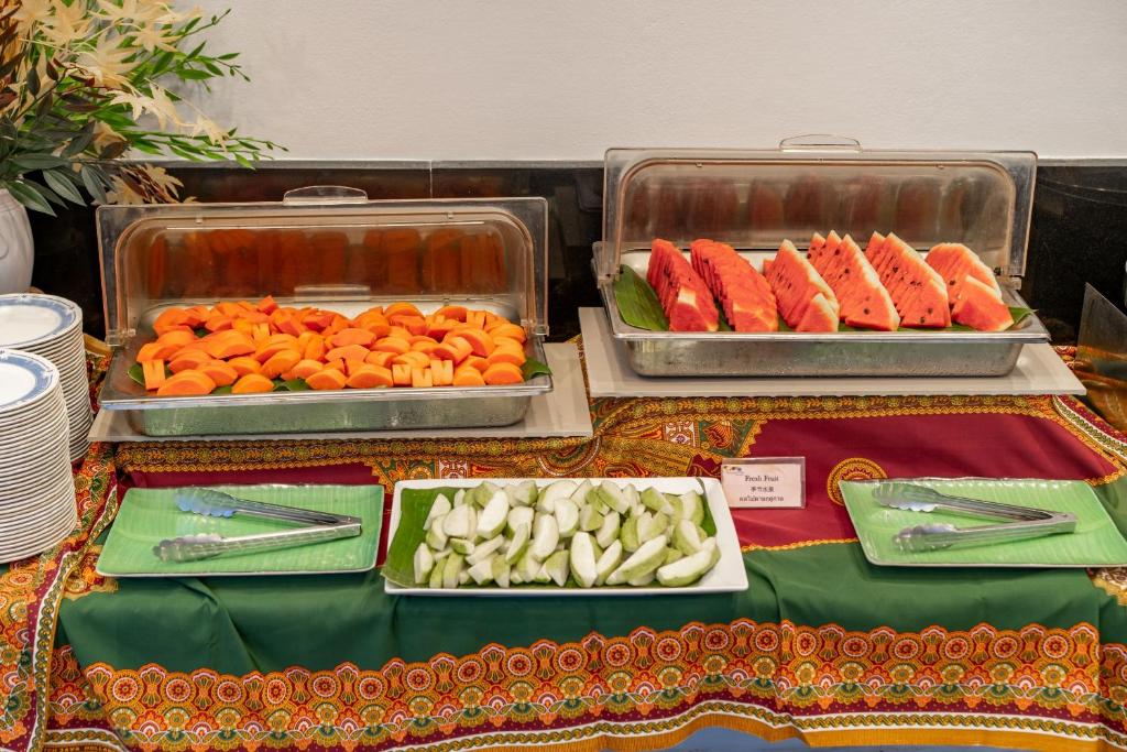 Svaigu augļu bufete ar dažādām šķēlēm, tostarp arbūziem, melones un citiem augļiem, pasniegta uz krāsaina galdauta.