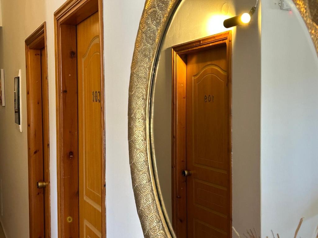 Spogulis un koka durvis koridorā, kur redzamas numuri 101 un 103. Siltā apgaismojuma atmosfēra rada mājīgu sajūtu.