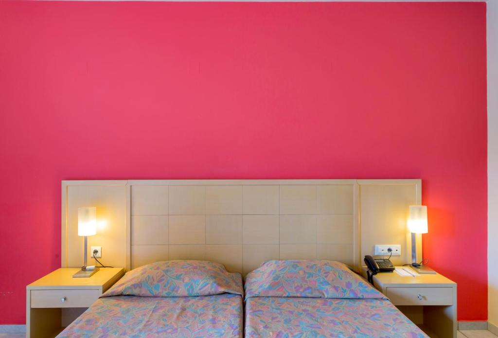 Numurs ar divām gultām un rozā sienām viesnīcā Dessole Malia Beach.