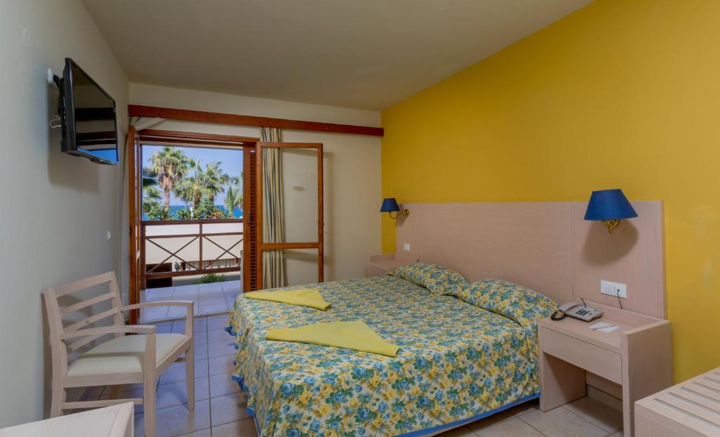 Numurs ar dzeltenām sienām un balkonu viesnīcā Dessole Malia Beach.