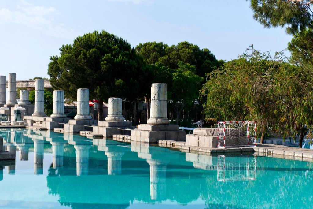 Xanadu Resort Hotel baseins ar kolonnām un zaļām priedēm