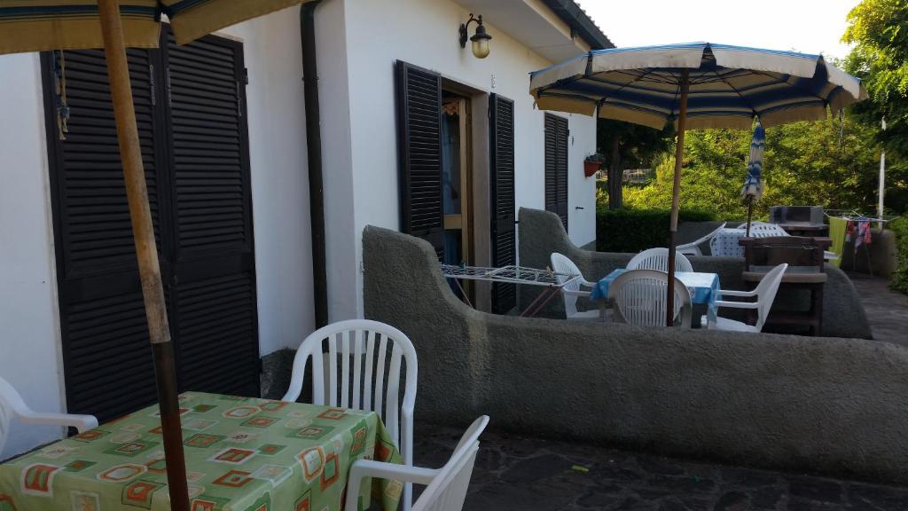 Āra terase ar galdiem un krēsliem, saulessargiem un mazām ēkām fona. Pavasara atmosfēra ar zaļu dabu apkārt.