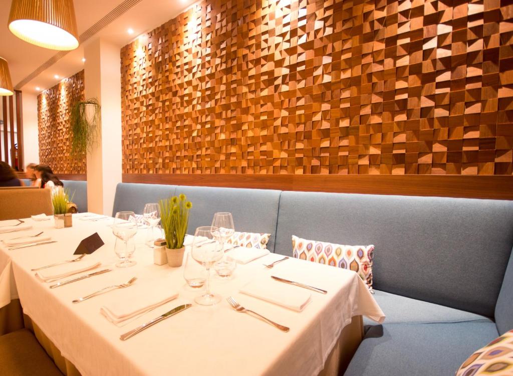 Mūsdienīga restorāna interjers ar koka sienu apdari, elegantām galda uzstādījumiem un komfortablām dīvānu sēdvietām. Ideāls vieta relaksējošām pusdienām vai vakariņām.