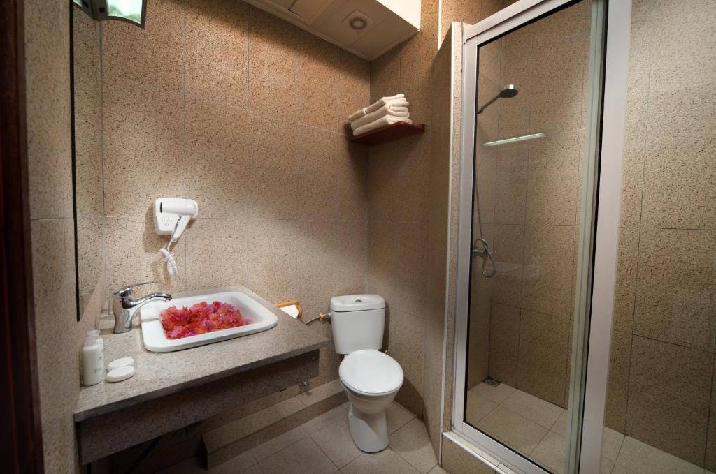 Mūsdienīgs vannas istabas interjers ar dušu, tualeti un izlietni, kurā ir ziedlapiņas un dvieļi. Svaigas un tīras līnijas rada relaksējošu atmosfēru.