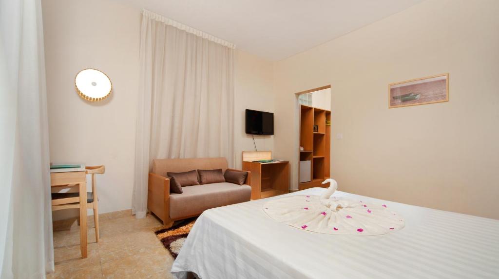 Mūsdienīgs viesnīcas numurs ar ērtu dīvānu, galdu un televizoru. Gulta rotāta ar dvieļu figūru, radot patīkamu atmosfēru.