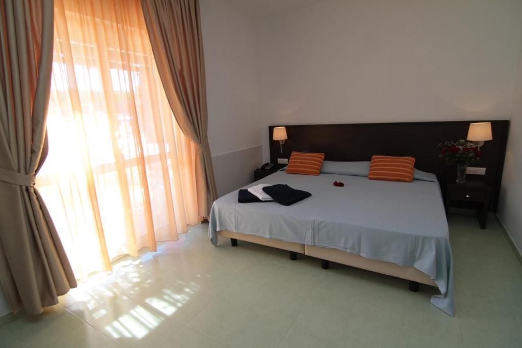 Mūsdienīga viesnīcas istaba ar plašu gultu, divām spilvenēnām ar svītrām un dabiskiem gaismas avotiem. Logi ar gaismiem aizkariem nodrošina siltu atmosfēru.