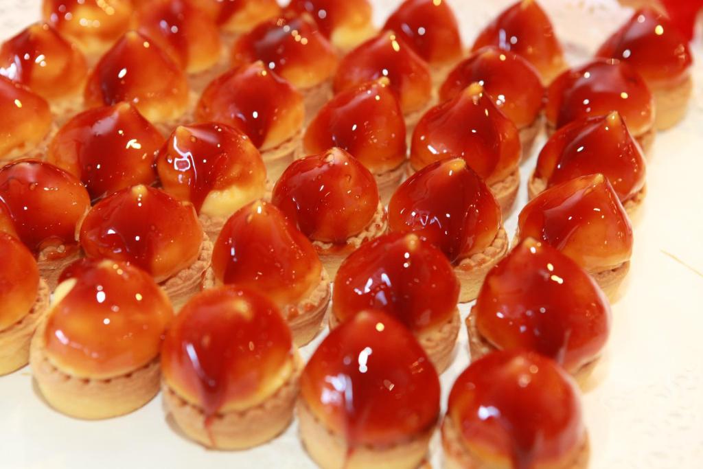 Saldēti mazi deserti ar glazūru, kas veidoti kā sirds formas, izkārtoti gleznaini.