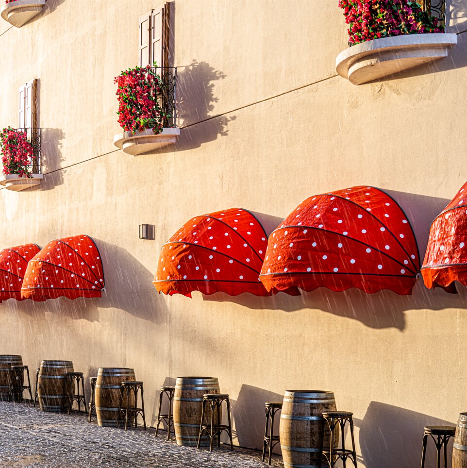 Voco Monaco Dubai fasāde ar sarkaniem nojumes un ziediem.