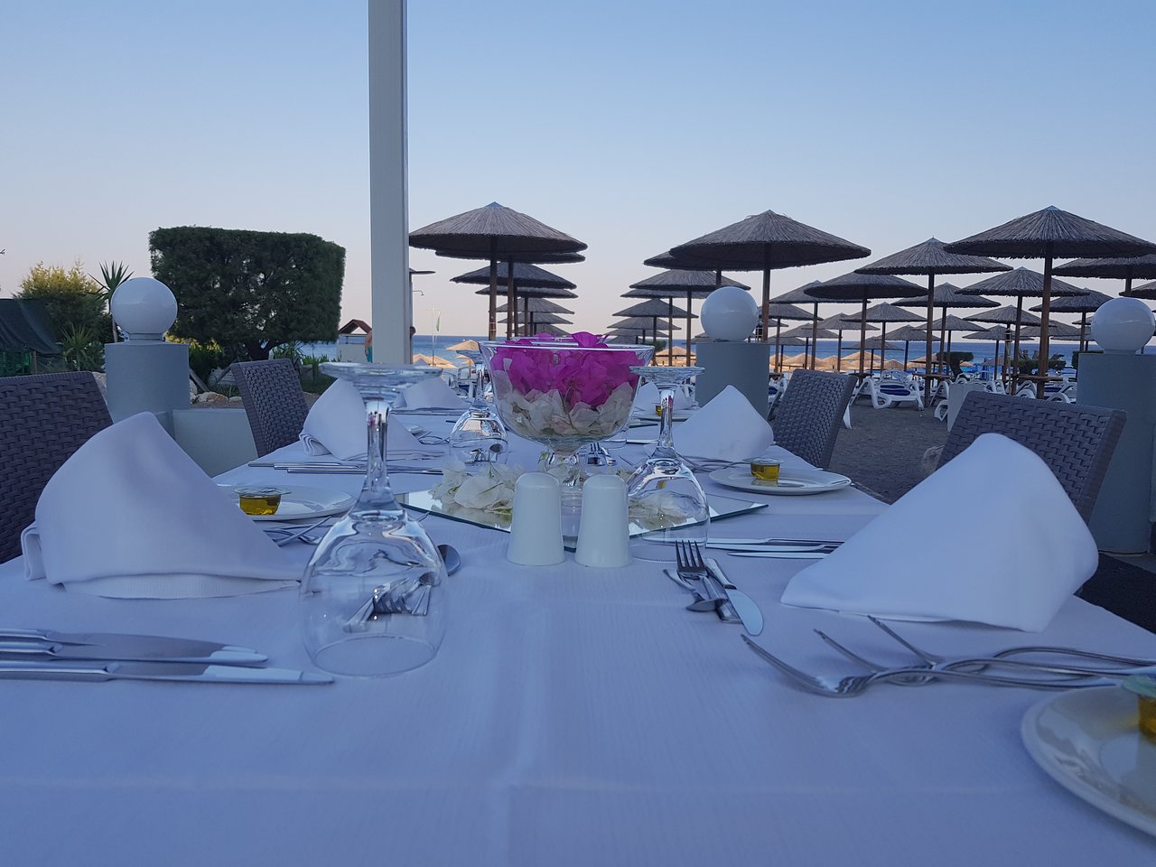 Eleganti klāts galds Olympos Beach Hotel āra restorānā ar skatu uz pludmales saulessargiem