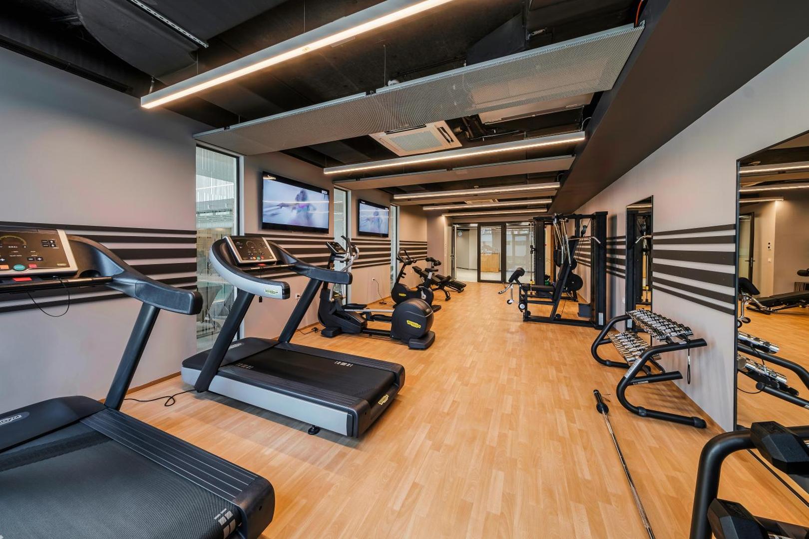 Voya Beach Resort moderns fitness centrs ar Technogym skrejceliņiem, velotrenažieriem un brīvo svaru zonu gaišās telpās