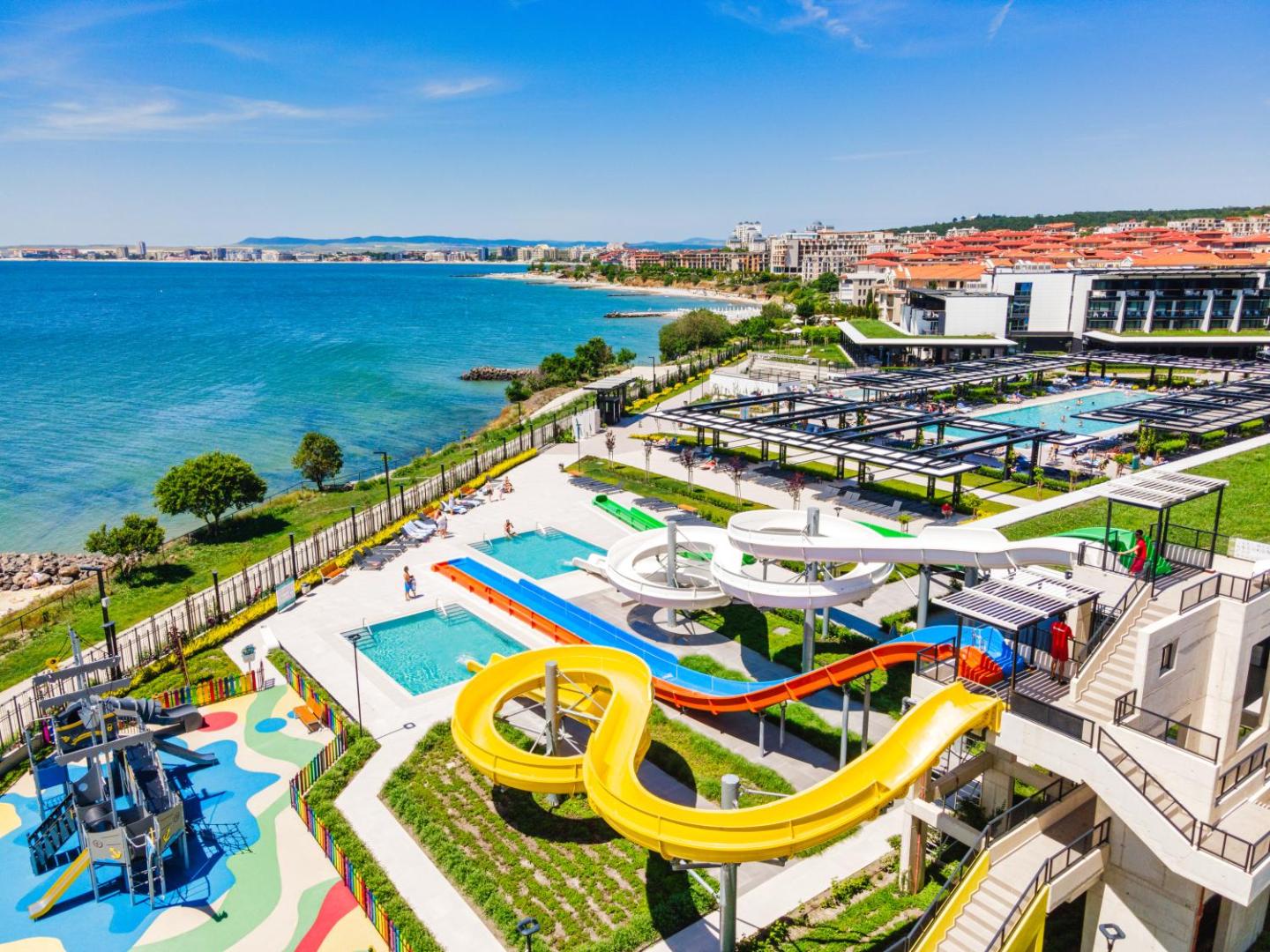 Voya Beach Resort panorāmas skats uz akvaparku, baseiniem un Melno jūru Bulgārijā — plaša teritorija ar ūdens slidkalniņiem