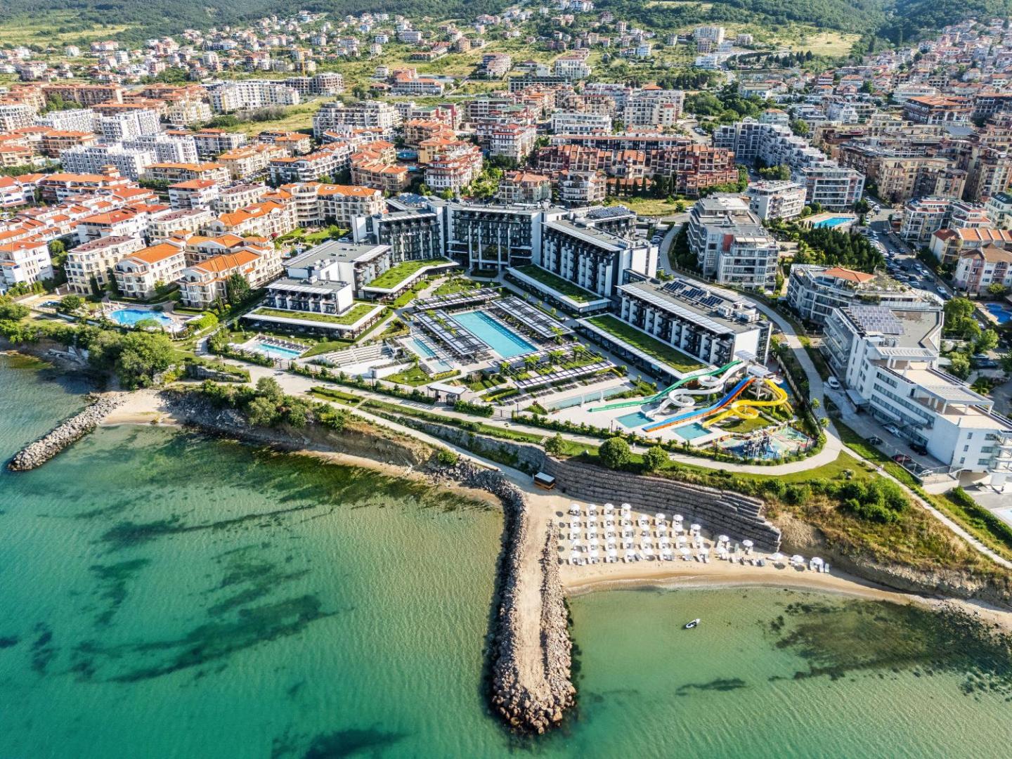 Voya Beach Resort panorāmas skats no putna lidojuma Sveti Vlasā, Bulgārijā — moderna viesnīcas ēka, baseini, akvaparks un privātā pludmale pie Melnās jūras