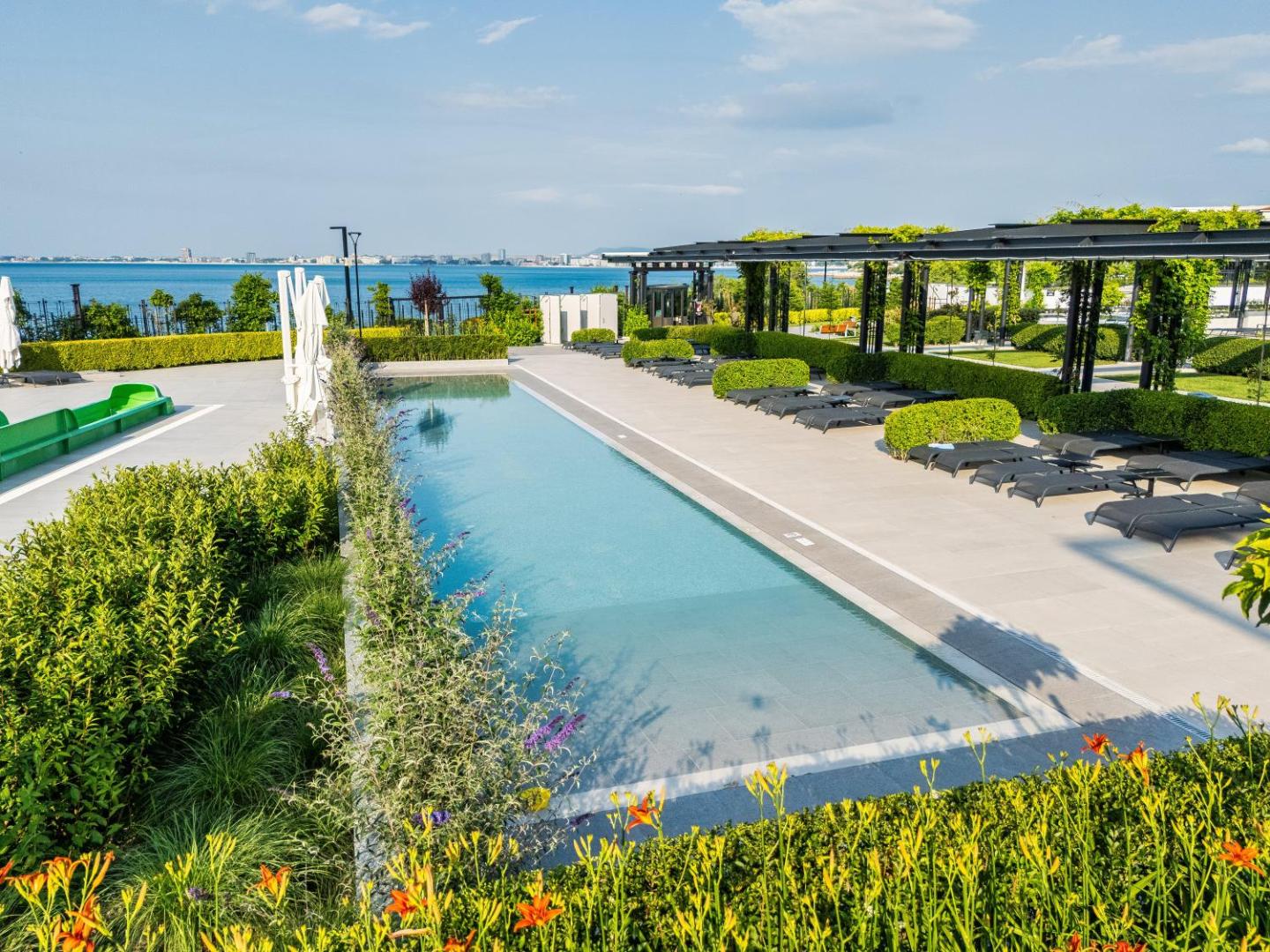 Voya Beach Resort bērnu baseins un atpūtas zona ar skatu uz jūru, dārza apstādījumiem un modernām nojumēm.