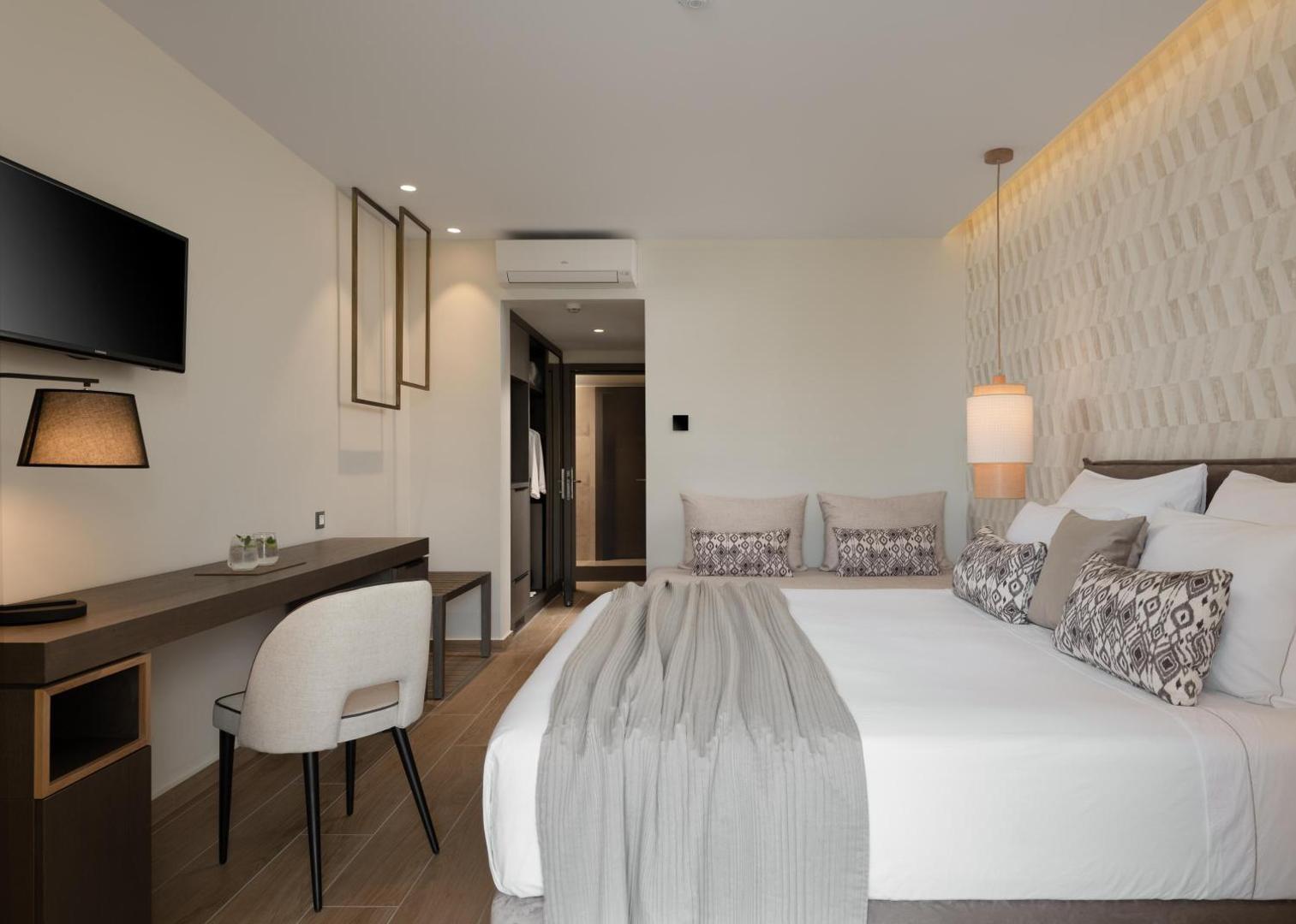 Theartemis Palace moderns viesnīcas numurs ar gaišu interjeru, darba zonu un gaisa kondicionieri Retimno kūrortā Krētas salā